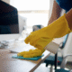 Someone wearing rubber gloves cleaning a desk
